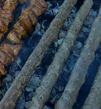 Seekh kababs and chicken tikka skewers on a charcoal grill