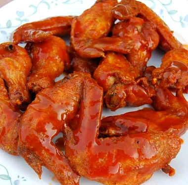 Chicken wings in a red sauce on a white plate