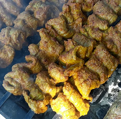 Chicken tikka skewers cooking over charcoal