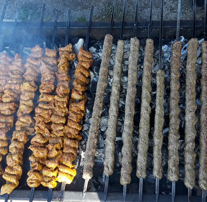 Chicken tikka and seekh kabab skewers side by side on a charcoal grill
